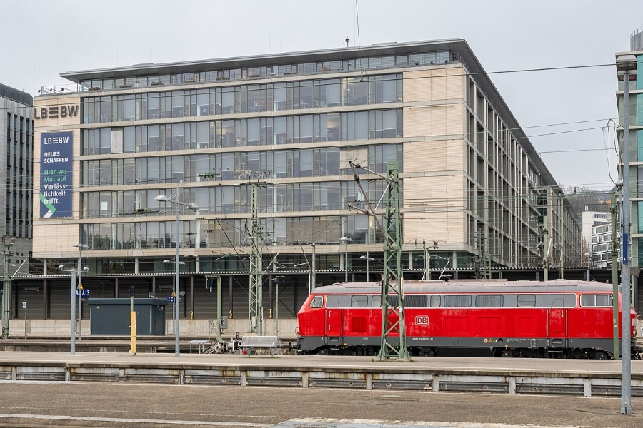 German Regional Day Tickets: Decision Trees for Maximum Savings 5 Red train positioned on tracks adjacent to a building, representing the public transport system in Baden-Württemberg.