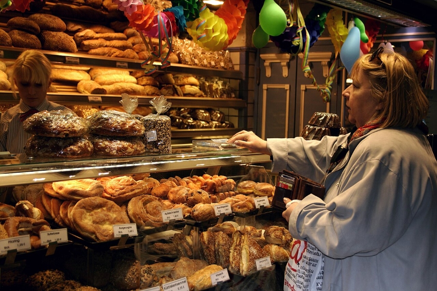 Sunday & Quiet Hours in Germany: The Complete Survival Guide 6 Woman inspects different types of bread displayed in a German bakery setting.