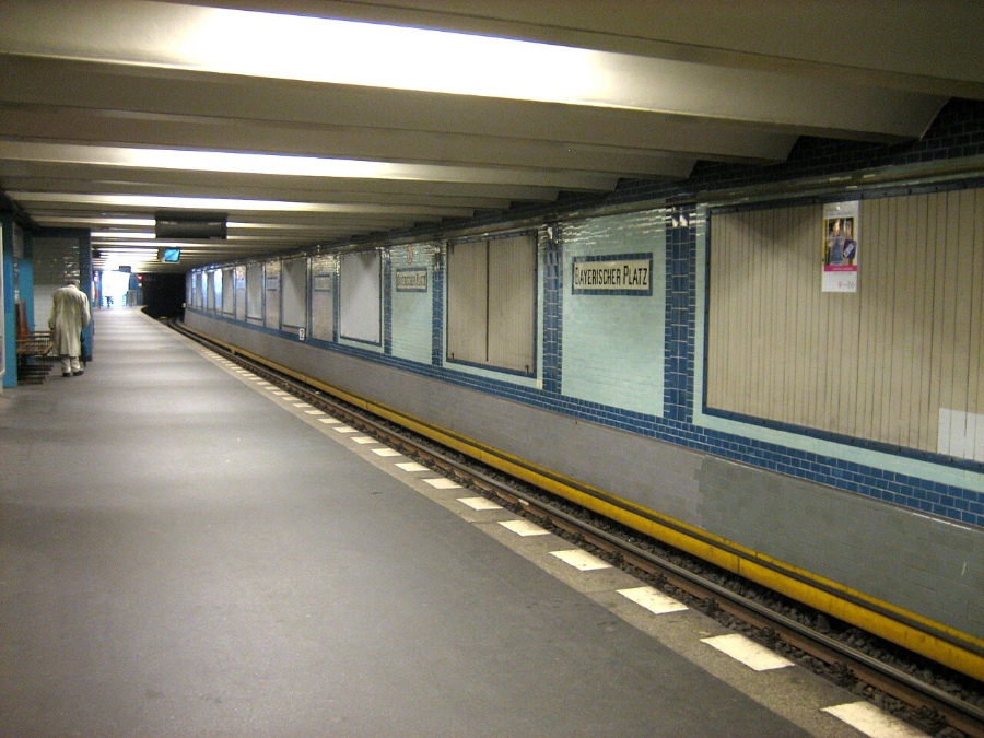 Parked train at Bayerischer Platz station, with visible platforms and nearby station amenities.
