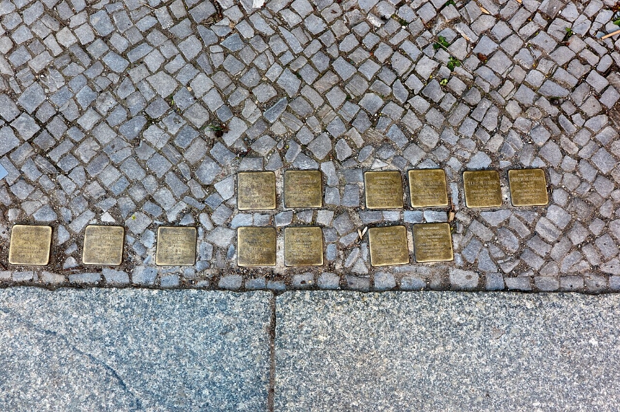 Several gold memorial plaques, known as Stolpersteine, set into the ground, honoring Holocaust victims in Berlin.
