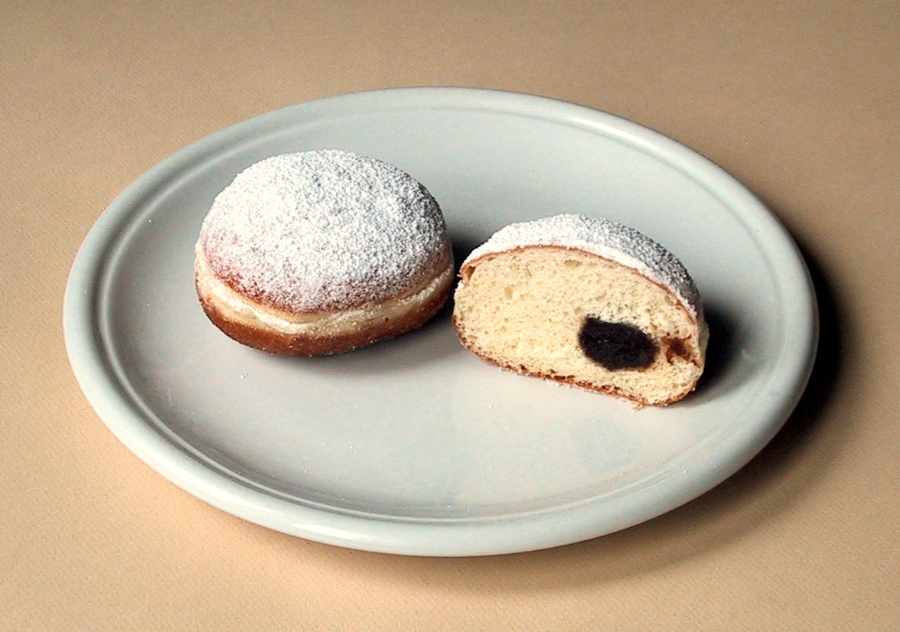 German Bread Culture: Bakeries, Loaves and Traditions 18 Close-up of a plate featuring a half-eaten Berliner doughnut alongside a half-eaten jelly doughnut, both with powdered sugar.