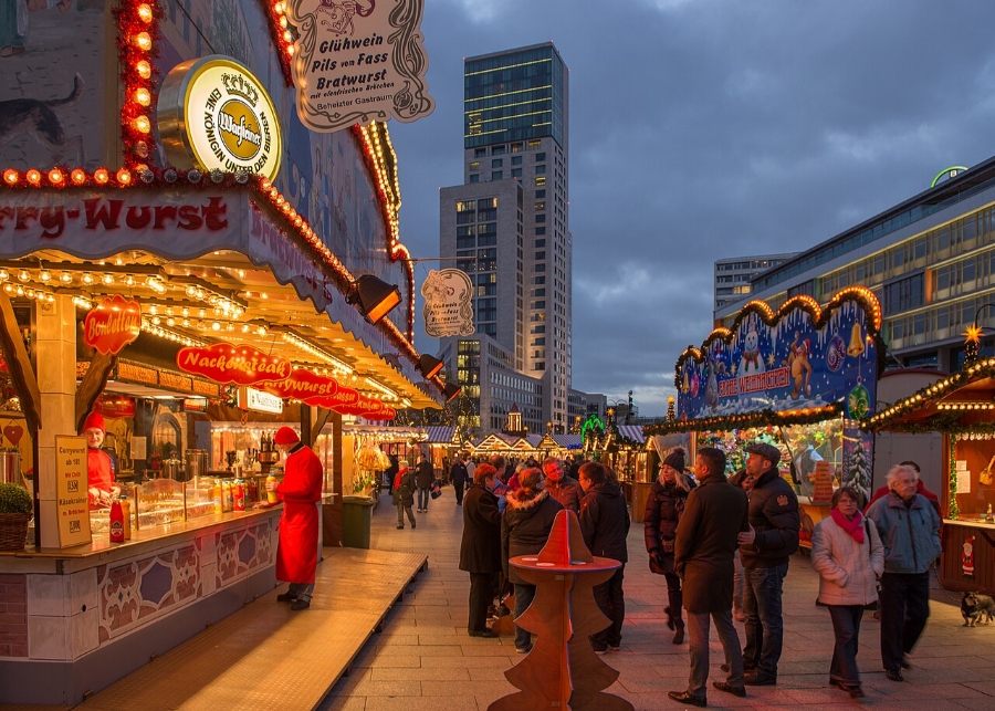 German Christmas Traditions: A Complete Guide 25 Crowds stroll through the festive Christmas market at Breitscheidplatz, Berlin, adorned with lights and holiday decorations.