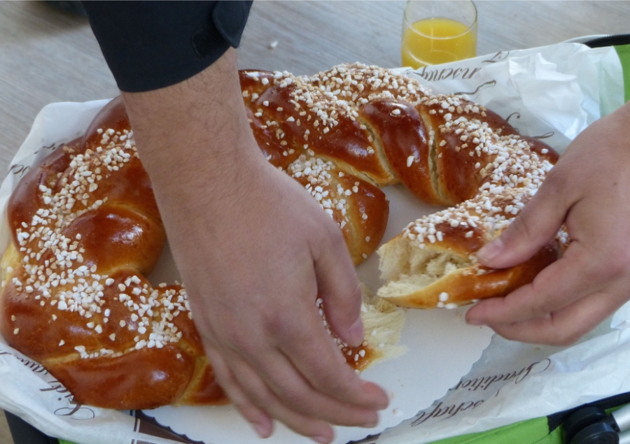 German Bread Culture: Bakeries, Loaves and Traditions 5 Hand holds a knife, cutting through a large loaf of bread on a kitchen counter.