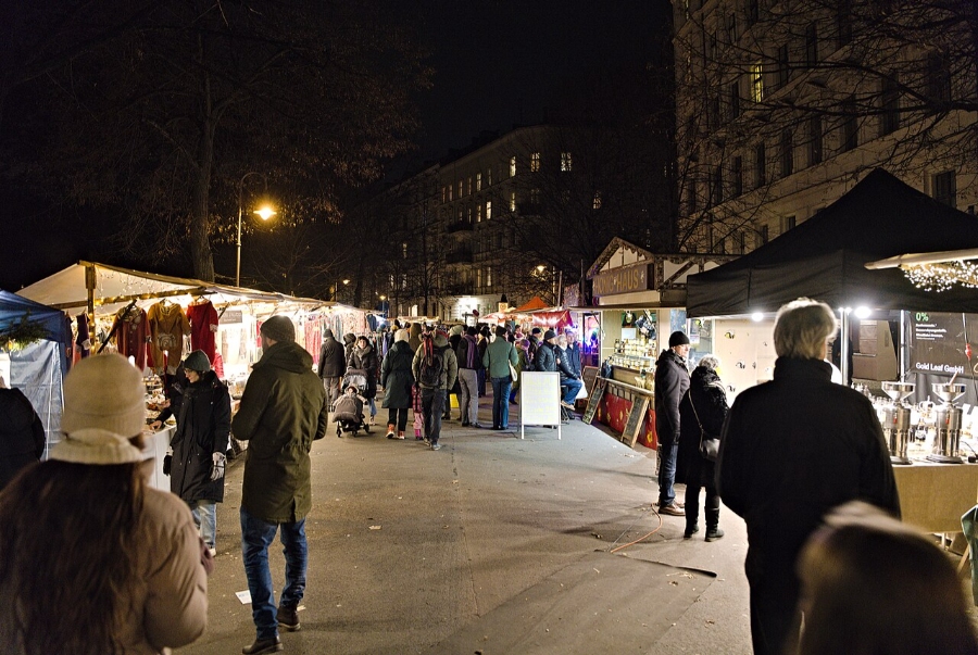 German Christmas Traditions: A Complete Guide 34 Bustling Christmas market in Berlin at night, with crowds exploring festive stalls and twinkling lights illuminating the scene.