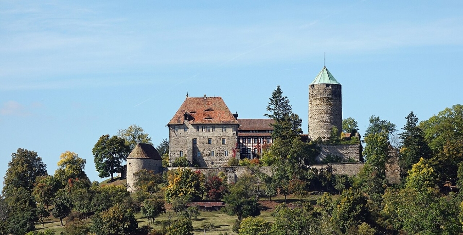 Exploring the German Castle Road: A Complete Guide 8 Colmberg Castle perched on a hill, surrounded by lush trees under a clear blue sky.