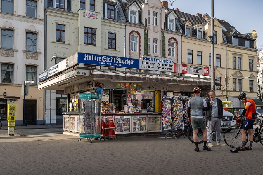 Sunday & Quiet Hours in Germany: The Complete Survival Guide 9 Couple stands at a newspaper stand, examining various newspapers and magazines on display.
