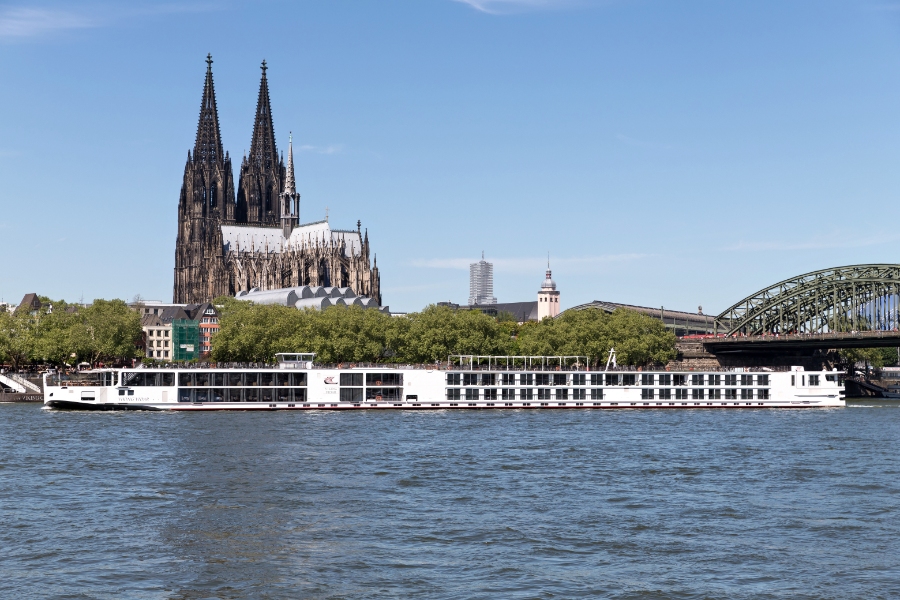 Middle Rhine Valley 17 The Viking Vidar river cruise ship glides by Cologne Cathedral, highlighting the blend of modern travel and historic landmarks.