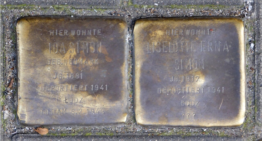 Two bronze Stolpersteine plaques embedded in a cement wall, commemorating victims of the Holocaust in Cologne.
