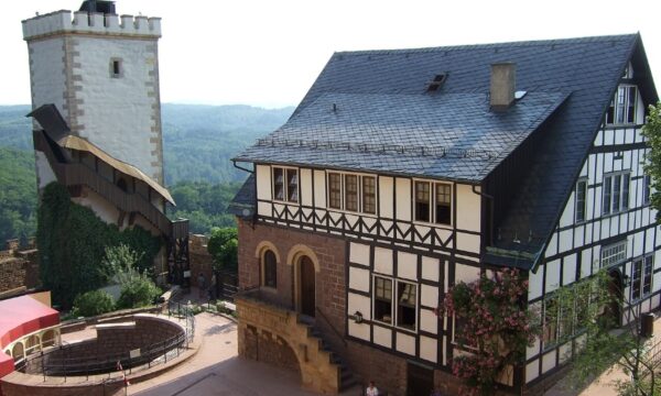 Courtyard of Wartburg Castle featuring a prominent tower and clock tower against a clear blue sky.