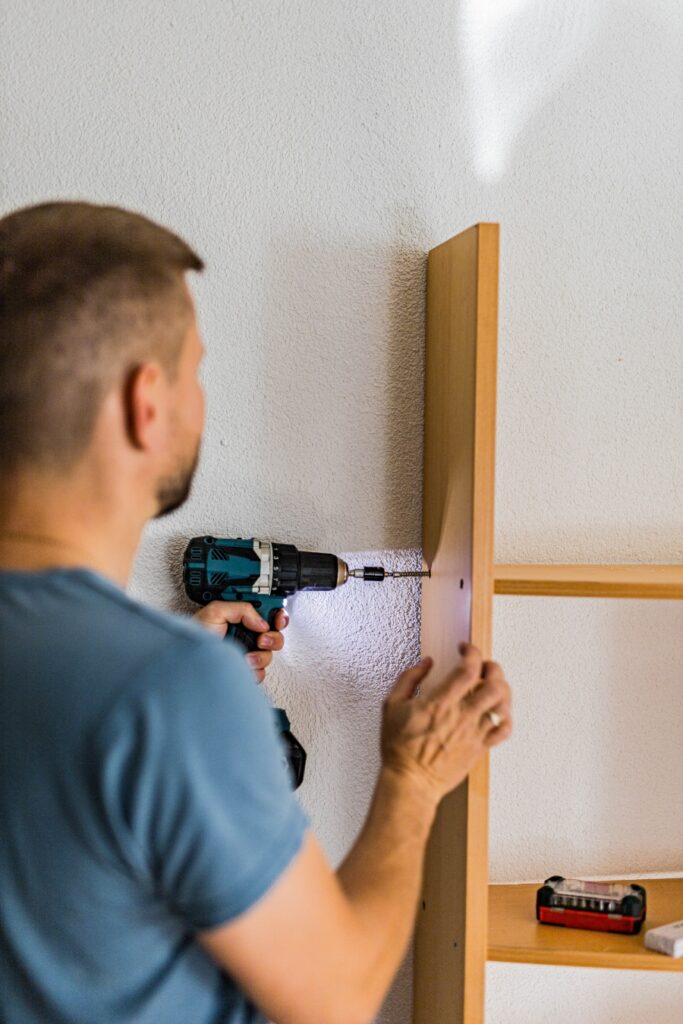 Sunday & Quiet Hours in Germany: The Complete Survival Guide 14 Young man using an electric drill to assemble a wooden shelf during a DIY home renovation project.