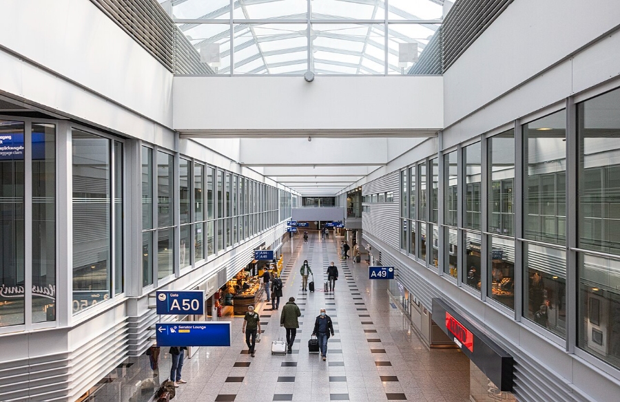 Düsseldorf Airport 10 Passengers walk through Düsseldorf Airport's A Gates terminal, featuring a spacious area with a large glass ceiling.