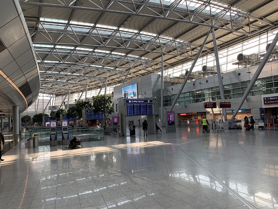 Düsseldorf Airport 16 Busy Düsseldorf Airport departure hall with travelers walking and checking in at various airline counters.