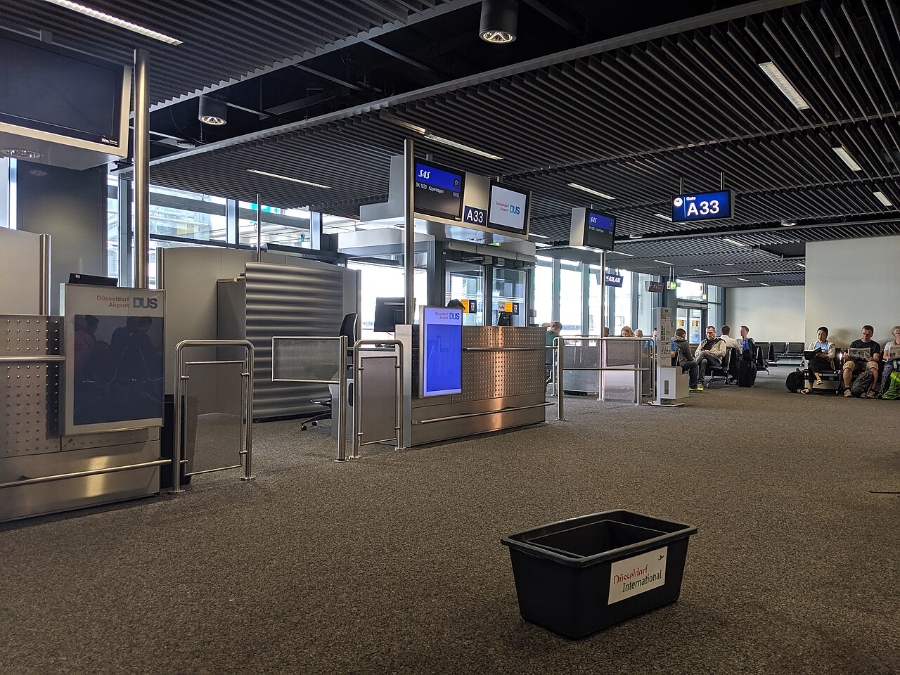 Düsseldorf Airport 7 Interior view of Düsseldorf Airport gate, showcasing numerous passengers seated and engaging in various activities.