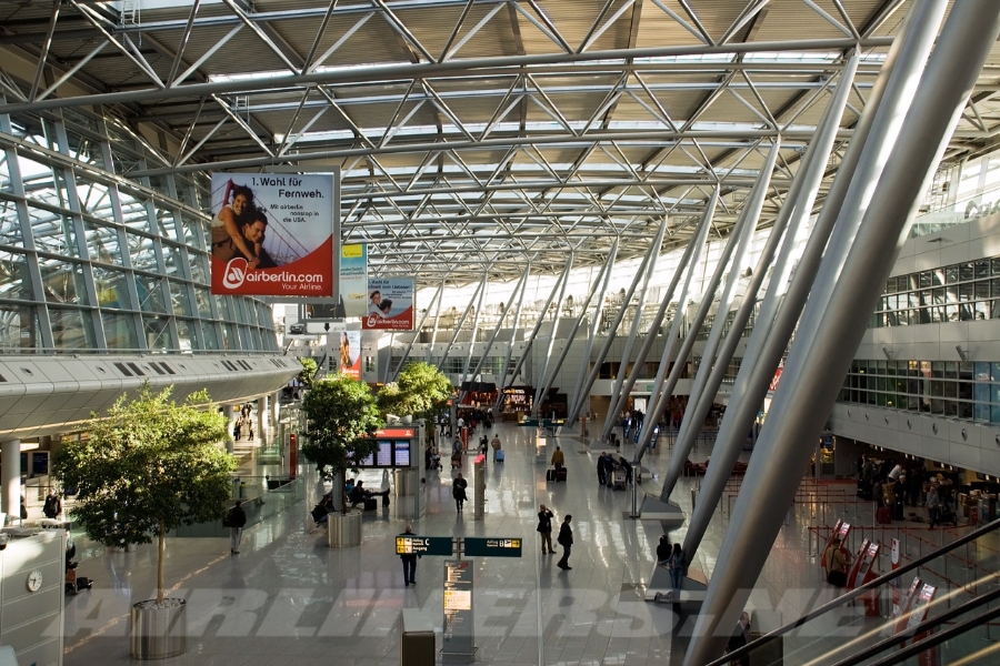 Düsseldorf Airport 14 The interior of Düsseldorf Airport terminal, featuring high ceilings, large windows, and travelers moving through the space.