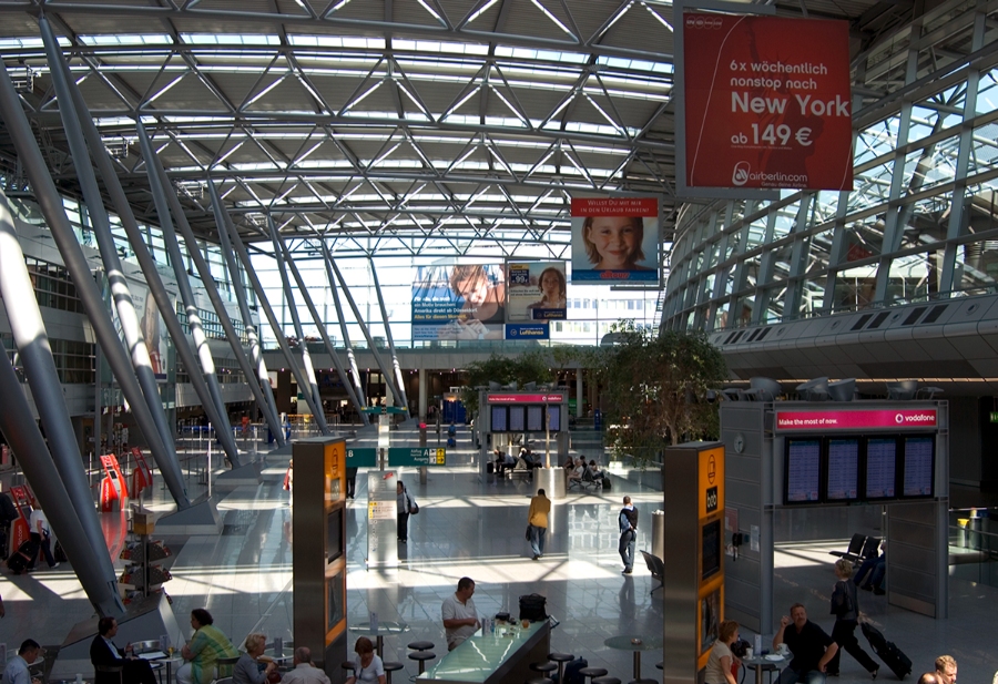Düsseldorf Airport 8 Interior of Düsseldorf Airport terminal bustling with travelers and shops, showcasing modern architecture and spacious design.