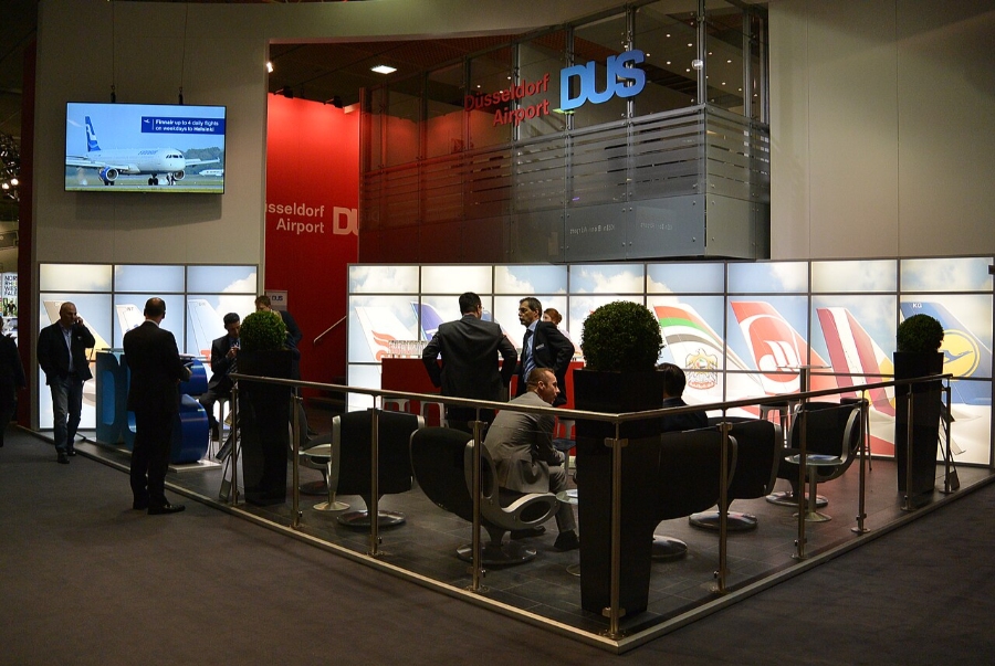 Düsseldorf Airport 5 Several individuals stand near a display case in the Düsseldorf Airport Lounge, examining the showcased items.