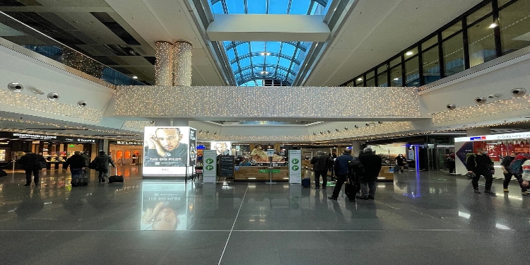 Frankfurt Airport 3 Interior view of Frankfurt Airport Terminal 1, featuring travelers walking and various shops and seating areas.
