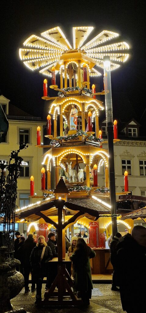 German Christmas Traditions: A Complete Guide 31 Vibrant Christmas market scene showcasing a tall, illuminated tower and decorative German Christmas pyramids.