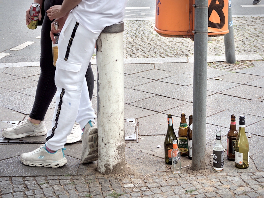 Pfand System Explained: Germany's Bottle Deposit Complete Guide 19 Man rests on a pole, with multiple Pfand bottles visible in the background, highlighting Germany's recycling culture.