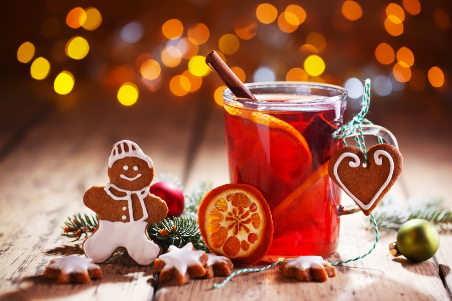 The Ultimate Guide to German Christmas Markets 7 Steaming glass of mulled wine with gingerbread cookies and colorful Christmas ornaments in the background.