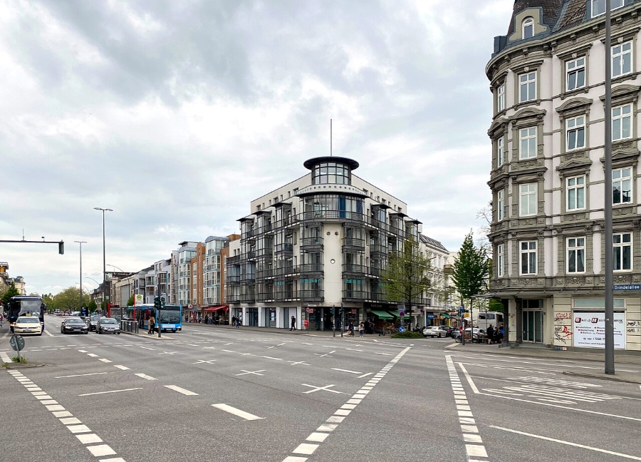 Grindelallee in Hamburg, showcasing a busy street scene with a bus and multiple cars in motion.
