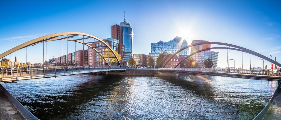 The iconic bridge over the river in Hamburg, Germany, framed by lush greenery and urban landscape.