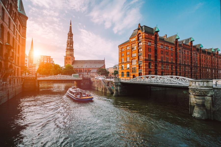Planning a Trip to Germany: Step-by-Step Guide for First-Timers 5 Sunset view of a touristic cruise boat in Hamburg's Speicherstadt, with bridges and old warehouses bathed in warm light.