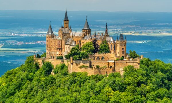 Hohenzollern Castle perched on a hill in the Swabian Alps, surrounded by lush greenery in Baden-Württemberg, Germany.