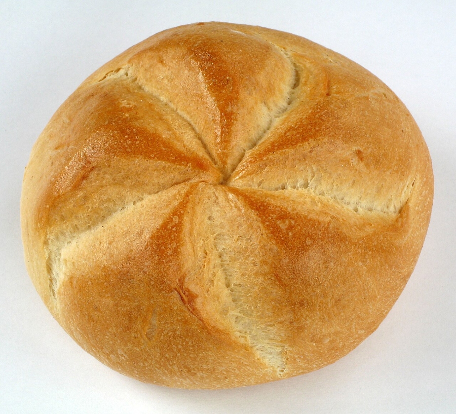 German Bread Culture: Bakeries, Loaves and Traditions 19 Freshly baked round Kaisersemmel on a white surface, emphasizing its golden color and traditional design.