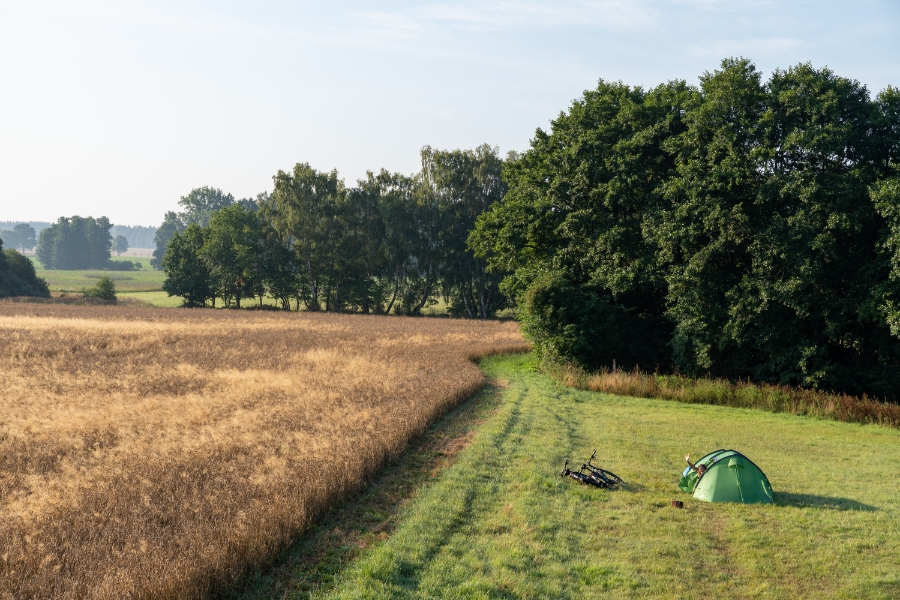 Green tent set up in a grassy field surrounded by trees in Marlow, Germany.