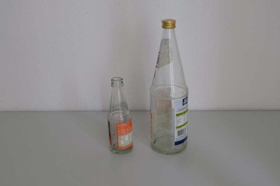 Pfand System Explained: Germany's Bottle Deposit Complete Guide 4 Close-up of two empty reusable bottles placed on a wooden table, showcasing their sleek design and clear material.