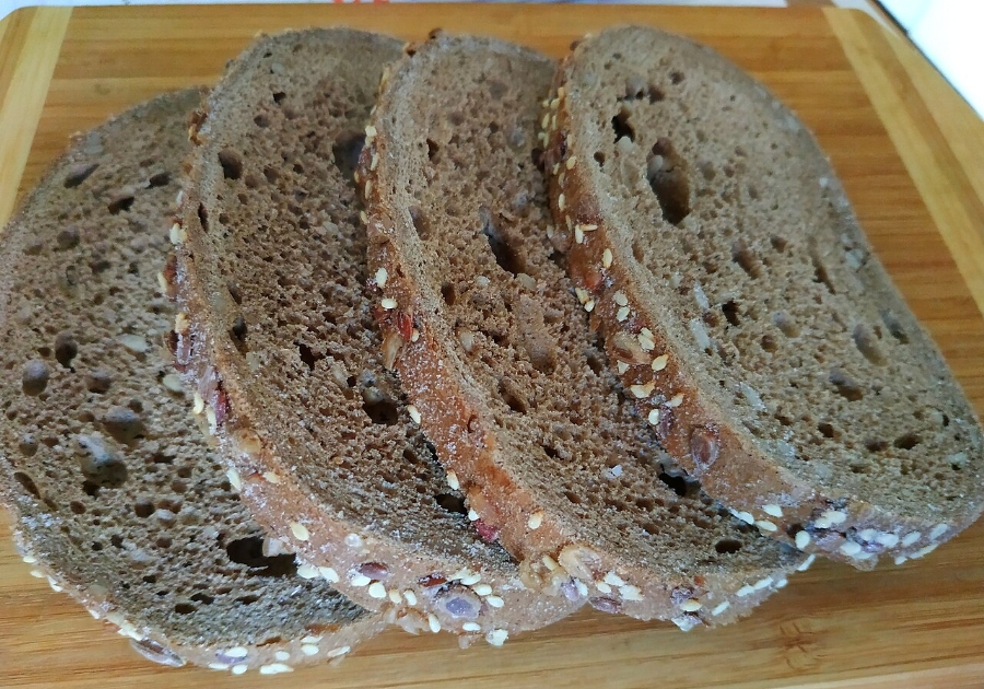 German Bread Culture: Bakeries, Loaves and Traditions 12 Slices of sunflower seed bread arranged on a wooden cutting board.