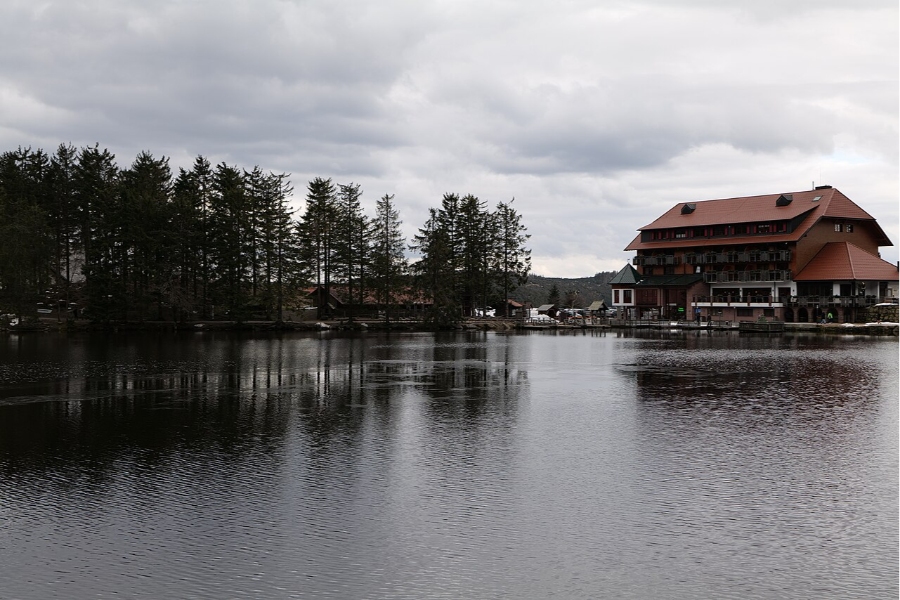 Mummelsee Lake in Germany featuring a prominent building on its shore, framed by trees and a serene landscape.
