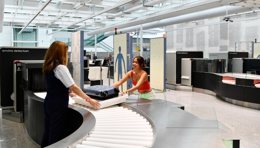 Munich Airport 12 Two women stand in front of a baggage conveyor belt at Munich Airport, preparing to check their luggage.
