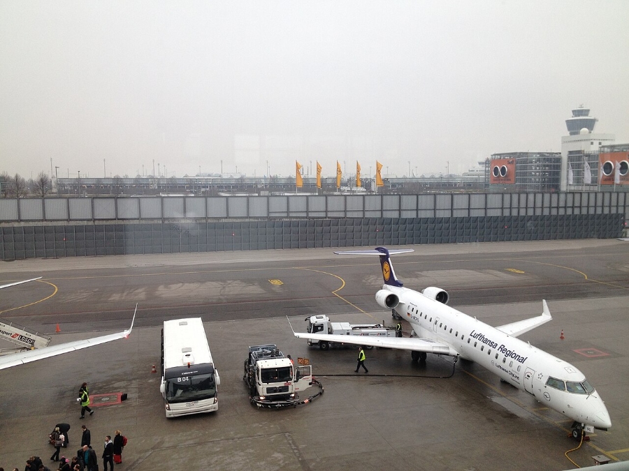 Nuremberg Airport 19 White aircraft stationed on the tarmac at Munich Airport, with a bus and a van in the foreground.