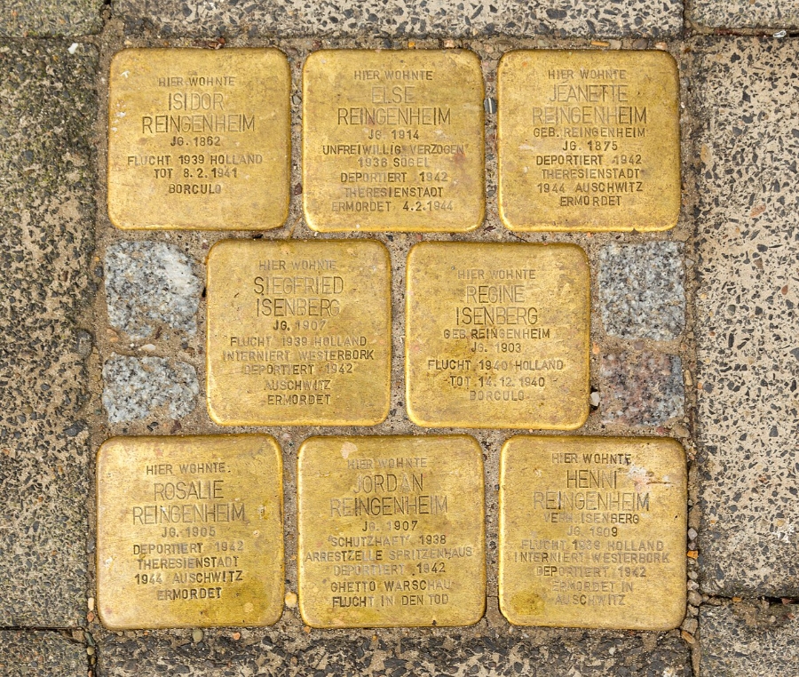 Several gold Stolpersteine plaques set into a sidewalk, honoring Holocaust victims in Munich, Germany.
