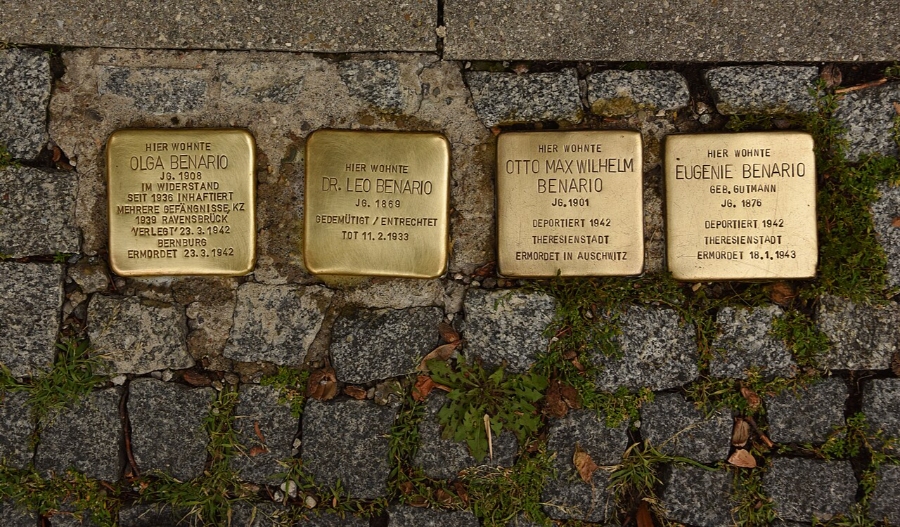 Close-up of three adjacent gold Stolpersteine plaques, honoring Holocaust victims in Munich's streets.
