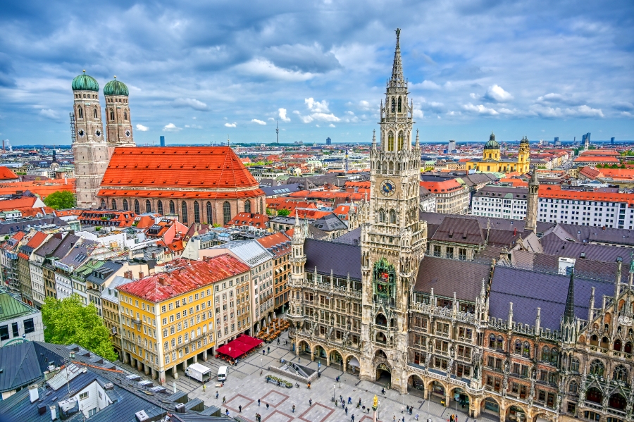 New Town Hall in Munich, Germany, featuring its iconic spires and the nearby cathedral against a clear blue sky.