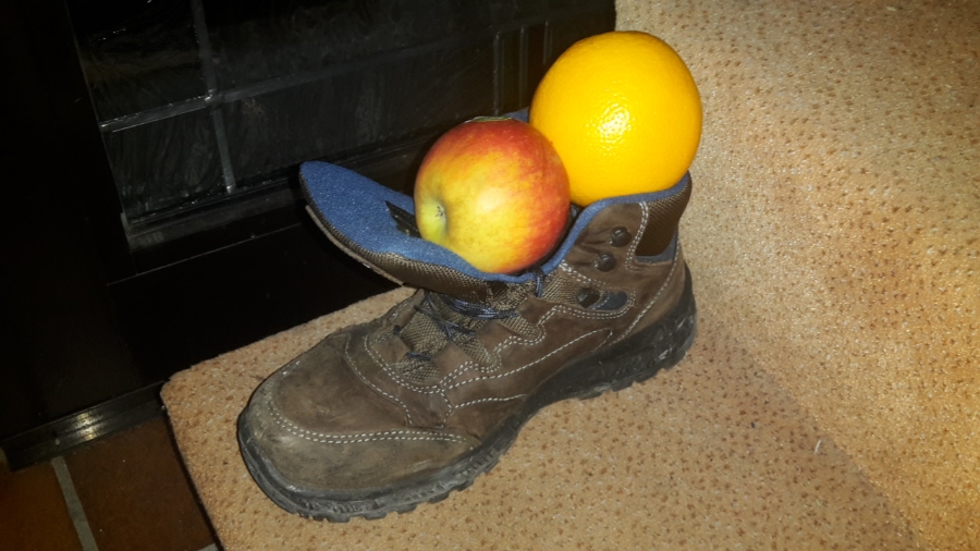 German Christmas Traditions: A Complete Guide 9 Children's shoes positioned at a door, containing an apple and an orange for the Nikolaustag tradition.