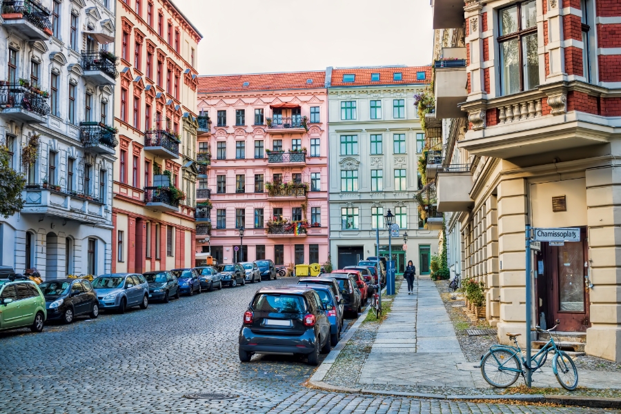Umweltzone Guide: Germany's Low-Emission Zones Explained for Tourists 16 Colorful buildings line a street with parked cars and bicycles, showcasing a typical urban scene in Germany.