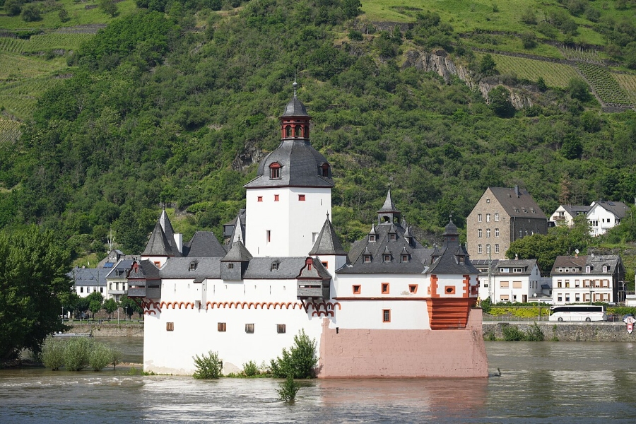 Middle Rhine Valley 8 Pfalzgrafenstein Castle stands majestically on a riverbank, surrounded by lush greenery and clear blue water.