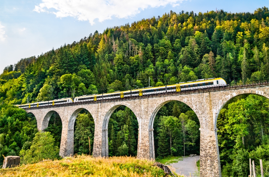 The Ravenna Bridge in Baden-Württemberg, Germany, features a train traversing over a river, surrounded by lush greenery.