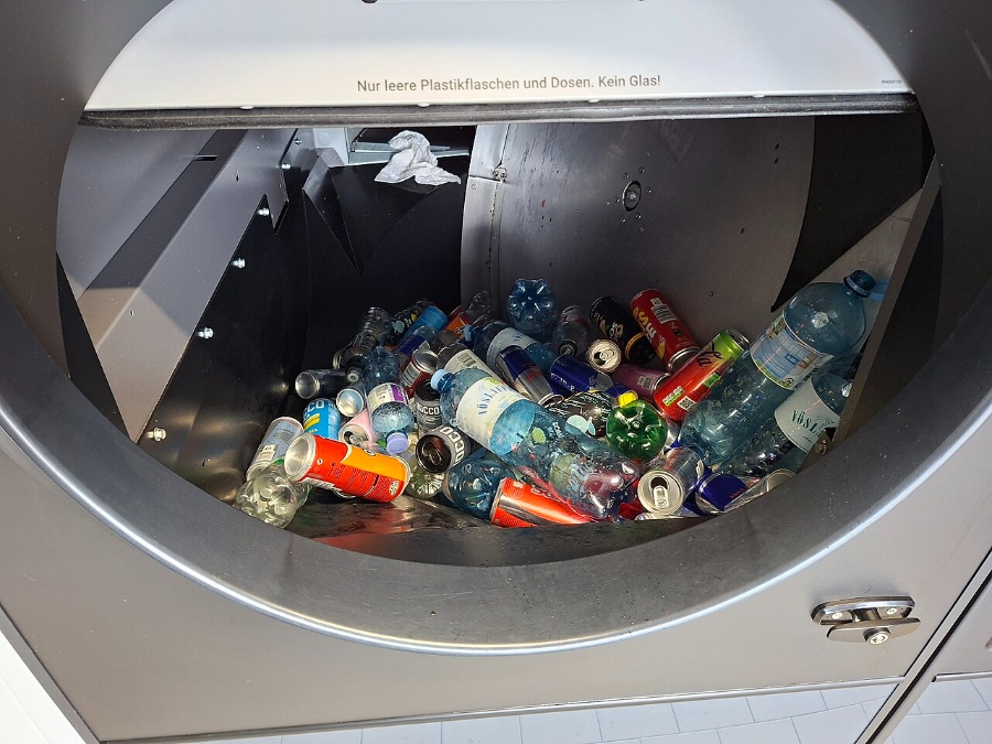 Pfand System Explained: Germany's Bottle Deposit Complete Guide 5 Container overflowing with various recycled bottles and cans, emphasizing waste management and recycling efforts.