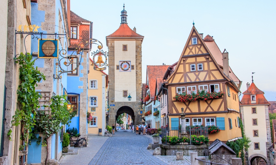 Exploring the German Castle Road: A Complete Guide 18 Narrow cobblestone street in Rothenburg ob der Tauber, featuring colorful buildings and a prominent clock tower.