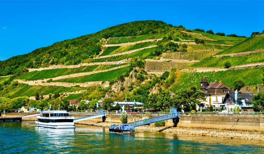 Middle Rhine Valley 7 Boat is docked on the river, with a scenic hill in the background in Ruedesheim am Rhein, Rheingau, Germany.