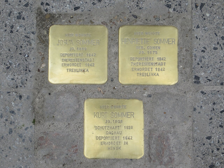 Close-up of three gold Stolpersteine plaques on the sidewalk of Ruhrstraße in Witten, Germany, honoring Holocaust victims.

