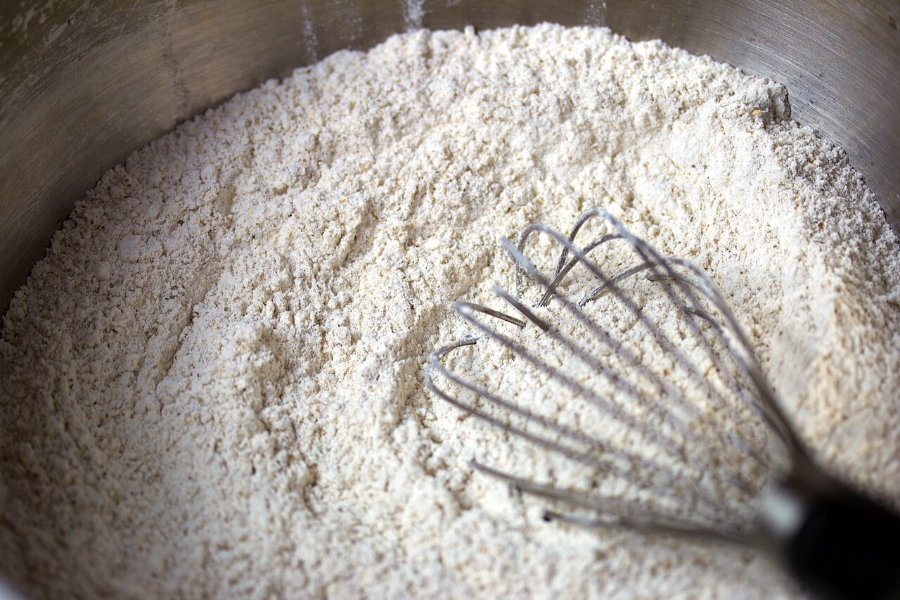 German Bread Culture: Bakeries, Loaves and Traditions 7 Bowl of rye flour with a whisk positioned inside, emphasizing the flour's earthy tone and smooth texture.