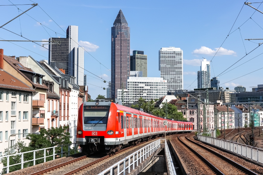 DB Deutsche Bahn's red S-Bahn train arriving at Frankfurt West railway station, showcasing public transport in the city.
