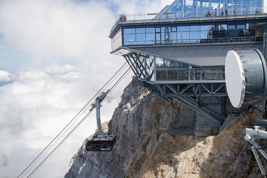 Zugspitze 8 Cable car glides above a snow-covered mountain peak, showcasing the stunning alpine landscape below.