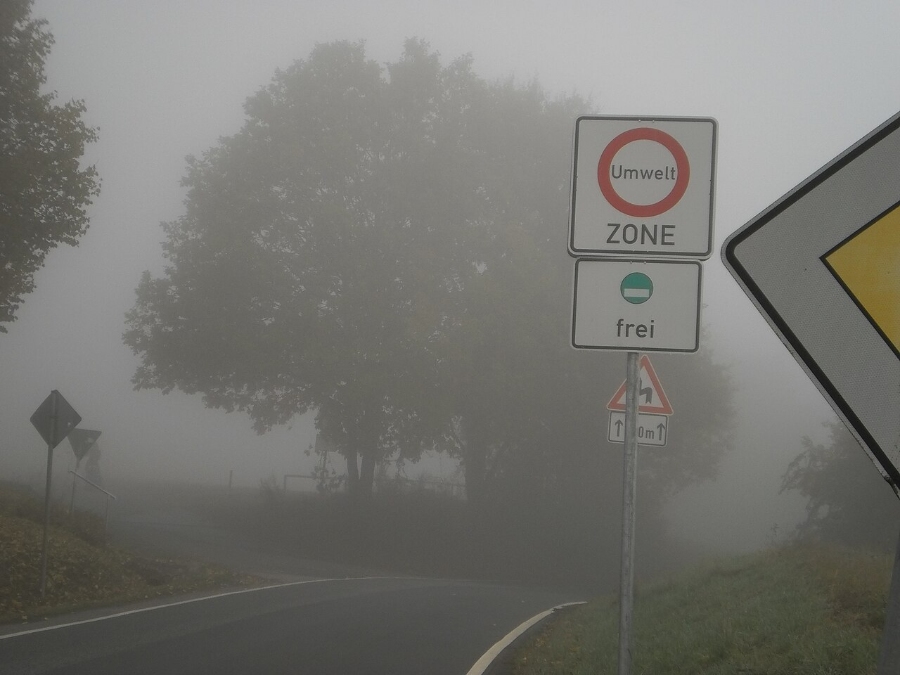 Umweltzone Guide: Germany's Low-Emission Zones Explained for Tourists 4 Street sign indicating an environmental zone, partially obscured by fog, with muted colors and blurred edges.